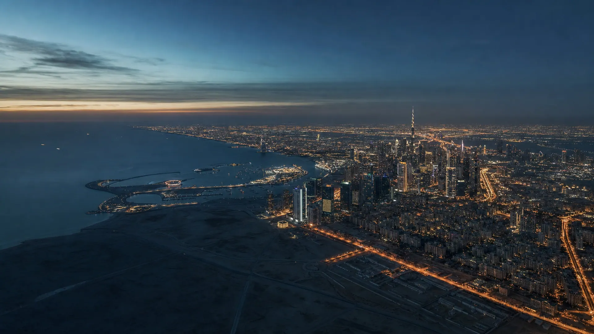 Aerial view of Dubai's skyline and coastline at blue hour